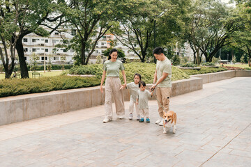 A Parents and children walk their dog together in an urban green space, sharing a peaceful outdoor...