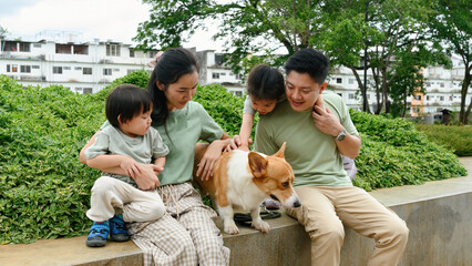 A parent and young children spending time outdoors together, petting their dog on a bench
