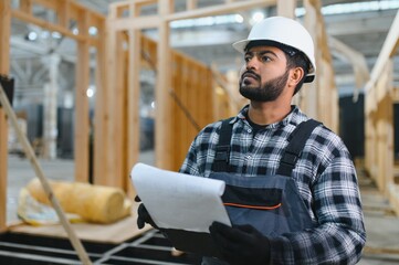 Construction of modular houses. Male indian construction worker in uniform and hard hat at...