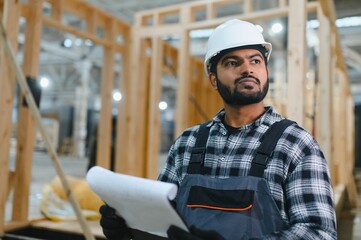 Construction of modular houses. Male indian construction worker in uniform and hard hat at...