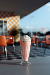Classic strawberry milkshake with whipped cream in retro diner at sunset