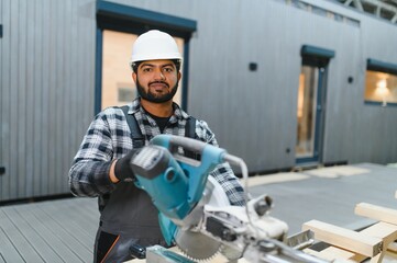 Indian Carpenter works with cutting boards on sawmills for the construction of wooden modular houses