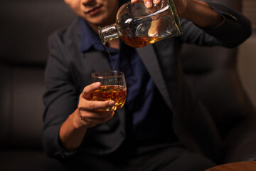 Businessman holding a glass of whiskey, sitting and drinking 