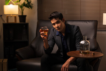 Businessman holding a glass of whiskey, sitting and drinking	