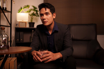 Businessman holding a glass of whiskey, sitting and drinking 