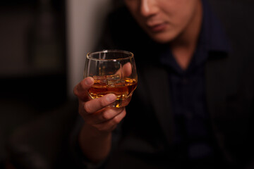 Businessman holding a glass of whiskey, sitting and drinking 