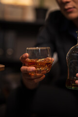 Businessman holding a glass of whiskey, sitting and drinking in a room	

