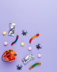 Assorted colorful candies over purple background with copy space