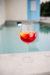 Refreshing red cocktail with orange slice by the pool