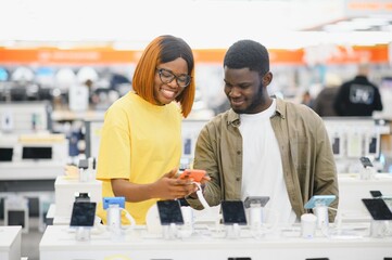 Obraz premium African american people buying new smartphone in mobile shop. Technology device shopping concept