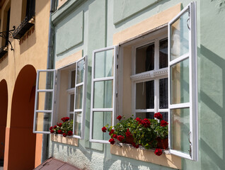 Charming windows with blooming geraniums in a picturesque village on a sunny day in spring