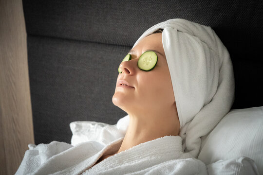 young woman getting eye nature treatment by cucumber at luxury spa resort. Wellness and healing concept.