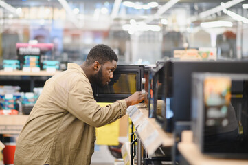 An African-American man is choosing a new microwave oven at an electronics store