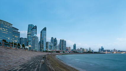Coastal city skyline with modern buildings and waterfront at dusk