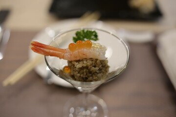 Elegant Japanese dish with shrimp, roe, and rice served in a martini glass at a restaurant in...
