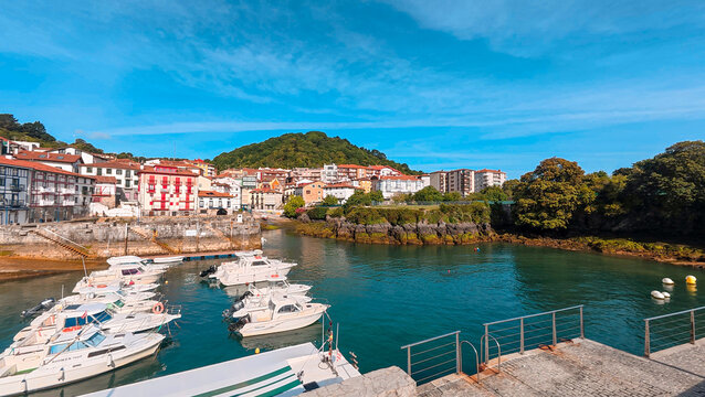 Scenic view of the charming fishing harbor of Bermeo, Basque Country, Spain, showcasing the colorful buildings of the old town and leisure boats floating on the tranquil water.
