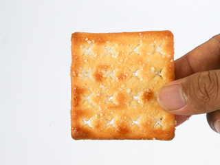 isolated hand holding a square sweet cracker with sprinkled sugar on top on a white background