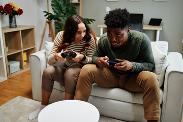 Excited couple playing video games at home on the couch