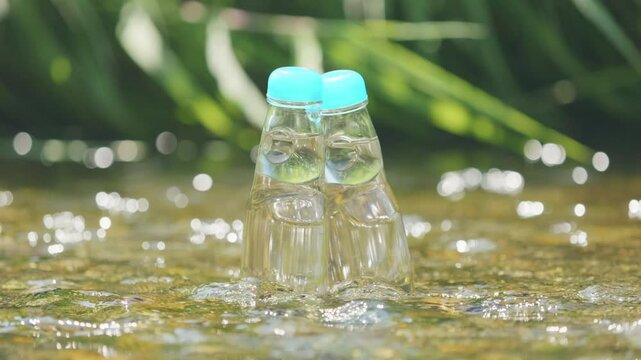 Two glass bottles of ramune soda in a cool river, Beverage or drink, 4K slow motion