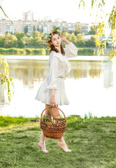 A girl in a wreath of flowers with a basket on Ivan Kupala Day.