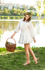A girl in a wreath of flowers with a basket on Ivan Kupala Day.