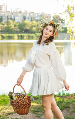 A girl in a wreath of flowers with a basket on Ivan Kupala Day.