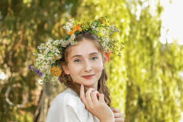 Girl in a wreath against the background of a river at sunset.
