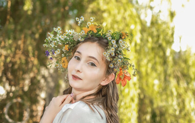 Girl in a wreath against the background of a river at sunset.