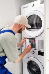 Washing machine technician performing maintenance in a modern apartment laundry room