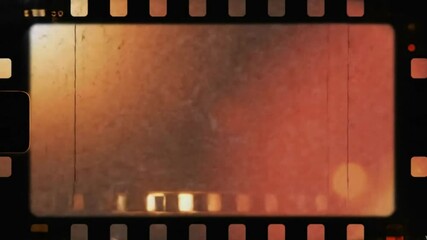 Old film strip with visible sprocket holes scratches and blurred warmtoned light spots on the frame - Powered by Adobe