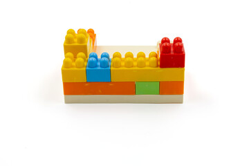 Colorful plastic building blocks assembled into a structure on white background