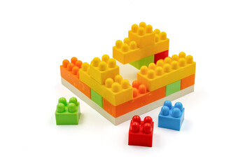 Colorful plastic building blocks assembled into a structure on white background