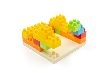 Colorful plastic building blocks assembled into a structure on white background