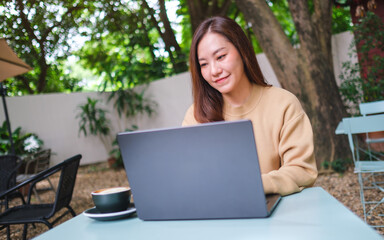Portrait image of a woman working on laptop computer in the outdoors