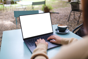 Mockup image of a woman working and typing on laptop computer with blank white desktop screen in...