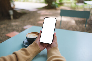 Mockup image of a woman holding mobile phone with blank screen in the outdoors