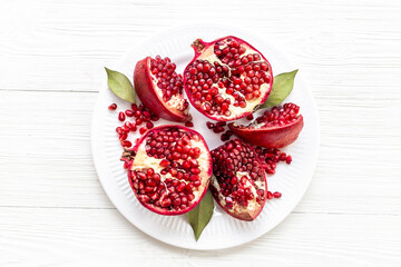 Top view of fresh ripe pomegranate and pieces on plate for eating, top view.