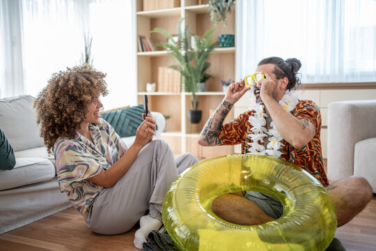 Couple planning summer vacation using smartphone and inflatable ring - Powered by Adobe