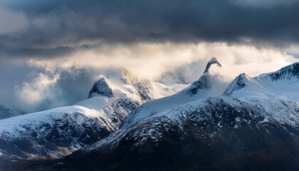 dramatic clouds hovering over snowy mountain peaks in norway