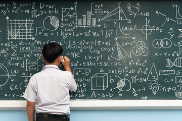 Student writing mathematical formulas on chalkboard with graphs and equations education learning...
