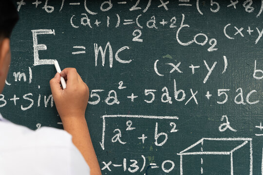 Close up student hand writing math equations on chalkboard education school learning knowledge concept