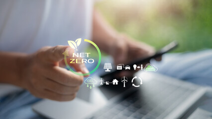 Hand pointing at Net Zero icon with renewable energy and carbon reduction symbols. Concept of...