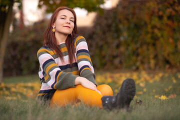 Portrait of a young beautiful cheerful red-haired girl in an evening autumn city.