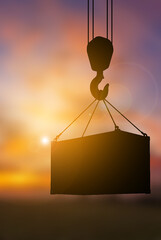 Crane hook lifting container sunset blur background