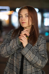 Portrait of a young beautiful cheerful red-haired girl in an evening autumn city.