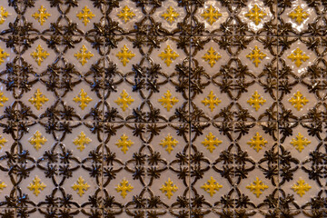 Close-up of vintage ceramic tiles featuring intricate yellow and brown patterns with a glossy...