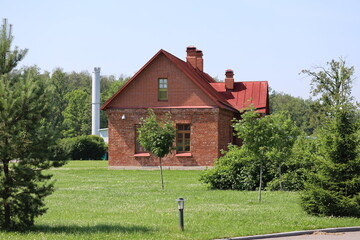 A single-story red brick house surrounded by a lush green field, perfect for rural or countryside...