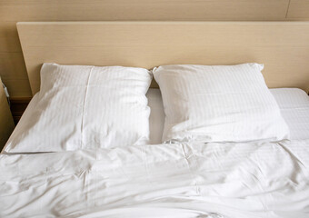 Two white comfortable pillows on the bed in the interior of a hotel room