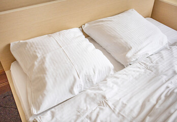 Two white comfortable pillows on the bed in the interior of a hotel room
