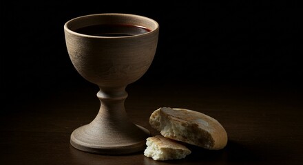 A wooden chalice filled with red liquid and broken bread are presented against a dark background, evoking tradition.